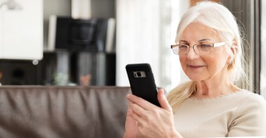 Beautiful senior woman texting at home